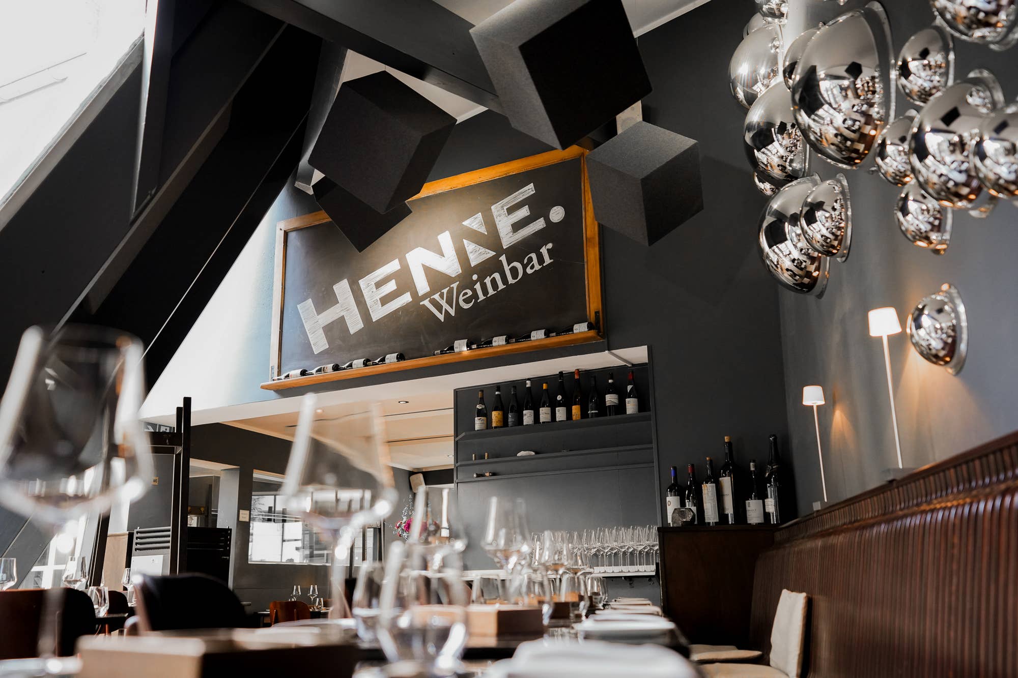 Schwarze Akustikwürfel an Decke von Akustikwerke in moderner Weinbar mit Discokugel-Leuchten