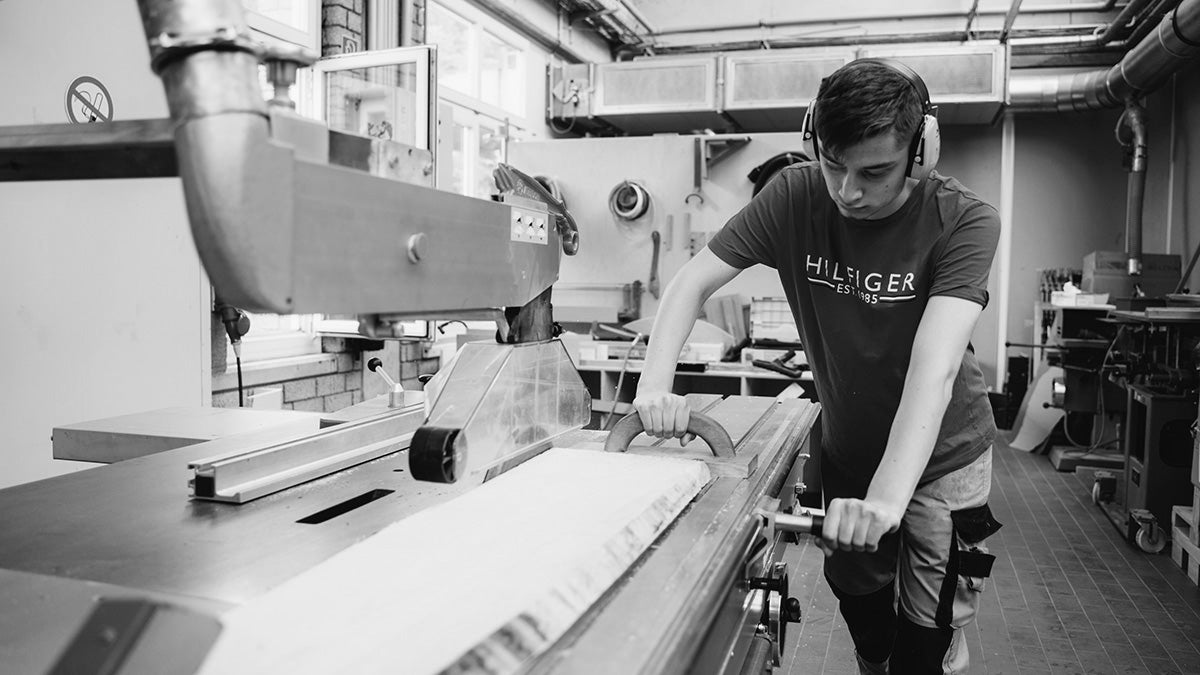 a man cutting wood pieces in the factory to make wall decore image   
